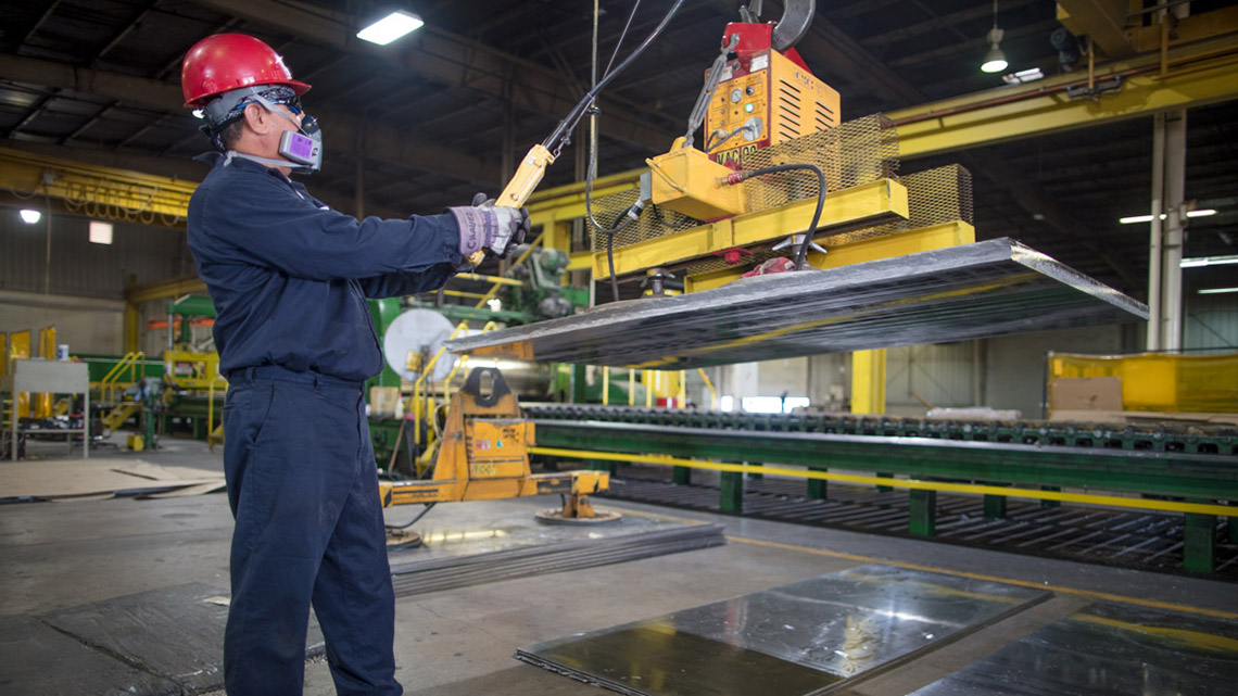An employee uses an overhead crane to move a large lead metal plate at Seafab Metals’ Casa Grande facility.