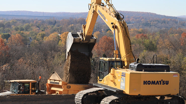 Large mobile equipment is used to remediate a former mine operation site according to government-approved closure plans.