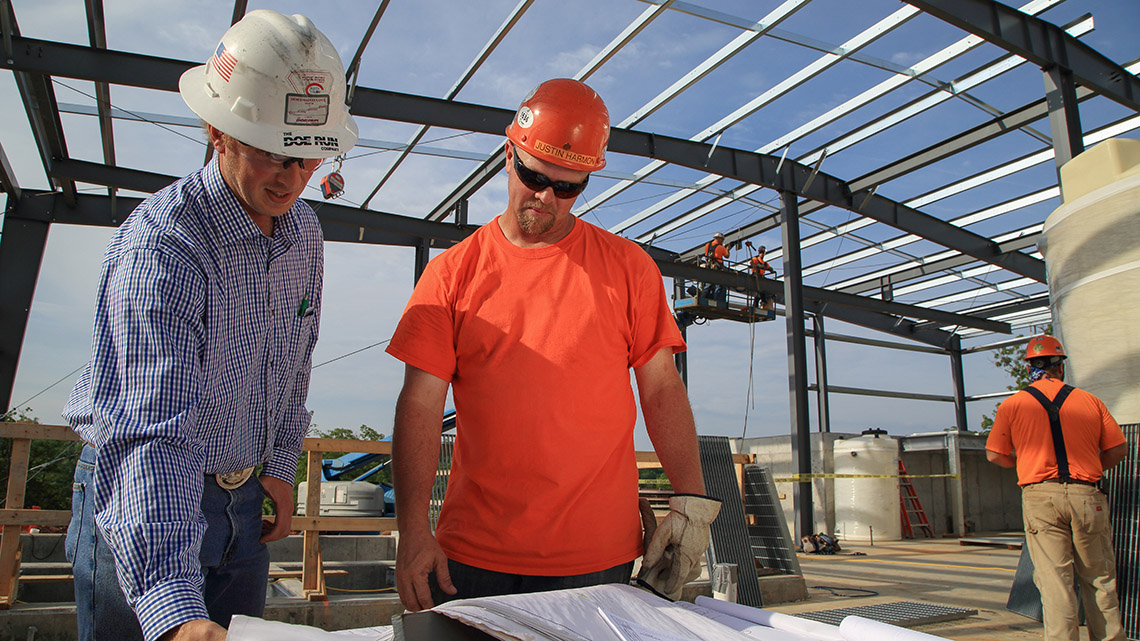 Doe Run employee and construction worker reviewing blueprints for a water treatment plant.