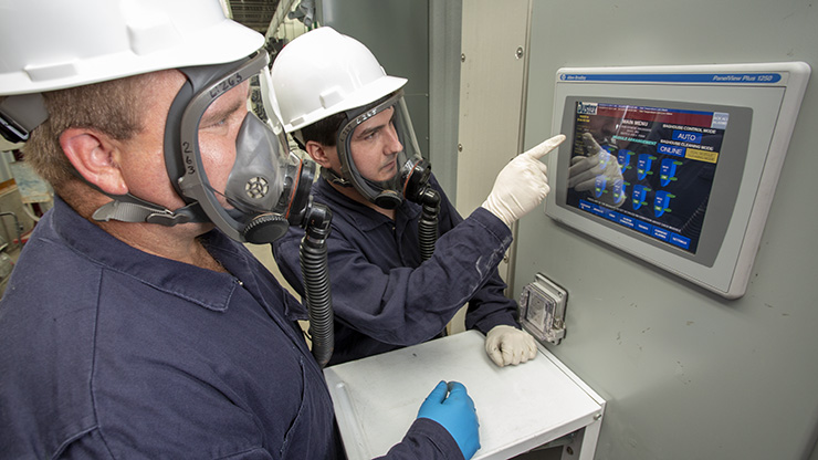 Two Resource Recycling employees check baghouse operational monitors.