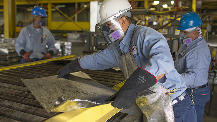 Seafab Metals Company employees pull finished, rolled lead metal from the rolling mill.